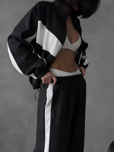 Detailed view of women's black and white color-block sports jacket and tracksuit pants.