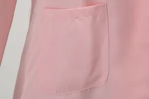Close-up detail of a professional pink blazer pocket showing soft fabric texture.