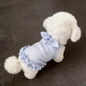 Detailed back view of a blue gingham pet dress with ruffles on a fluffy white dog.
