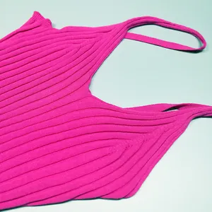 Détail d'une robe en tricot côtelé rose vif avec décolleté en V et texture.
