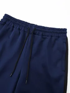 Close-up detail showing the elastic drawstring waistband of navy blue sports trousers