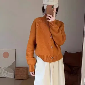 Vista detallada de un cárdigan de punto naranja con cuello alto y botones grandes