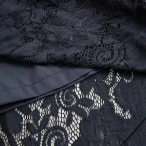 Macro detail showing the intricate black floral lace fabric with navy blue lining layers.