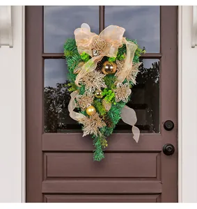 Golden Christmas teardrop swag with pine needles and ornaments hanging on a brown door.
