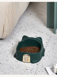 Close-up view of a dark green lucky cat shaped pet bowl on a modern terrazzo floor
