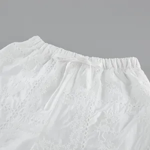 Détail en gros plan d'un pantalon large brodé blanc avec une taille à cordon réglable