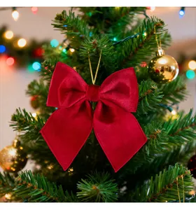 Red velvet bow ornament hanging on a festive Christmas tree with glowing lights.