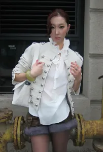 Détail d'une veste courte blanche de style militaire avec boutons argentés et col volanté