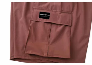 Detailed macro shot of a brown cargo pocket on men's quick-dry sports shorts featuring a logo