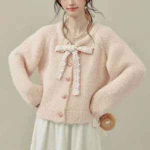 Dettaglio di un cardigan in maglia rosa con un delicato fiocco di pizzo a fiori.