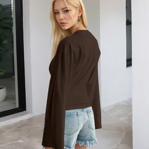 Seitenansicht eines blonden Models in einem dunkelbraunen Langarmshirt mit weiten Ärmeln