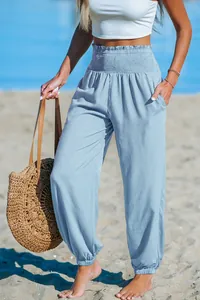 High-waisted light blue beach joggers with smocked waist and pockets in a beach setting.