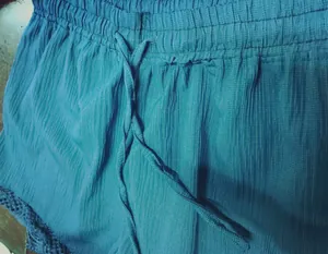 Vue détaillée du tissu texturé bleu sarcelle et du cordon de serrage du short femme.