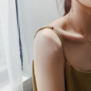 Dettaglio ravvicinato della spallina sottile di un lussuoso top in raso verde oliva