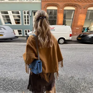 Vista posteriore di un elegante poncho marrone con orlo a frange in un contesto urbano