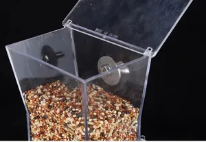 Nahaufnahme eines transparenten automatischen Vogelfutterspenders mit Vogelfutter