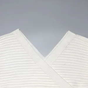 Close-up detail of a white V-neck knitted sweater showing the fine ribbed fabric texture quality.