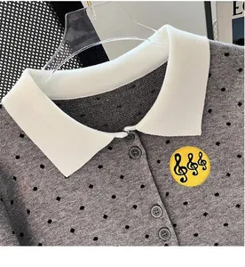 Close-up of gray polka dot cardigan with white lapel collar and music note embroidery.