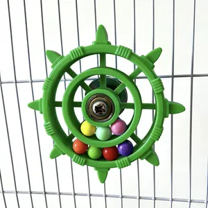 Close-up detail of green plastic bird toy rudder with colorful rolling beads in cage