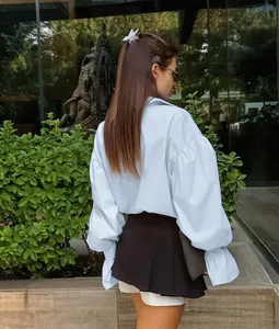 Detail view of white puff sleeve shirt with ruffled cuffs shown on a model outdoors.