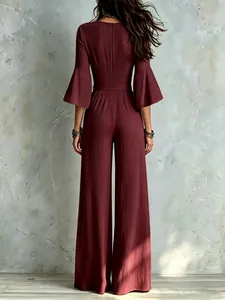Back view of a burgundy wide-leg jumpsuit with bell sleeves and a belted waist