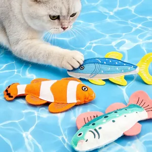 Detailansicht einer Katze, die mit bunten Plüschfischen auf Wasser-Hintergrund spielt