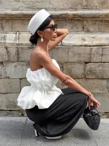 Side view detail of elegant white strapless peplum top styled with black wide trousers