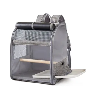Detail view of bird carrier backpack showing pull-out cleaning tray and wooden perch