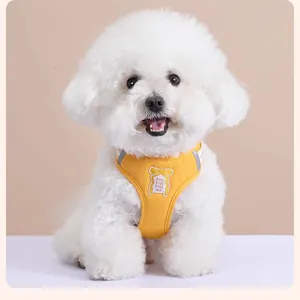 Vue de face d'un harnais jaune pour chien avec un patch noeud sur un Bichon Frisé blanc.