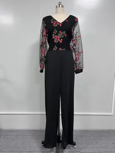 Detalle del mono negro con bordado floral y mangas largas de malla transparente.
