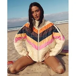 Retro chevron quilted jacket featuring vibrant multi-color stripes in a beach setting