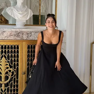 Elegant black square neck sleeveless midi dress shown in a luxury indoor lifestyle setting.
