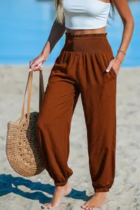 Detailed view of women's brown high-waisted smocked joggers perfect for beach vacations