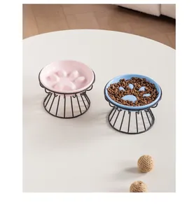 Detail view of pink and blue ceramic paw-shaped slow feeder bowls on black wire stands