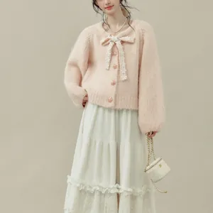 Dettaglio del cardigan in maglia rosa con fiocco delicato e bottoni floreali decorativi