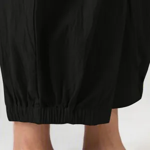 Close-up detail of the gathered elastic ankle cuff on black cotton linen harem pants