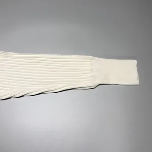 Close-up detail of a white ribbed knit sweater sleeve showing premium texture and cuff design