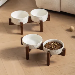 White ceramic pet bowls with paw patterns on a raised wooden stand for cats and dogs