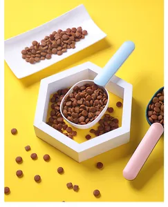 Detalle de cucharas para comida de mascotas azul claro y rosa sobre fondo amarillo