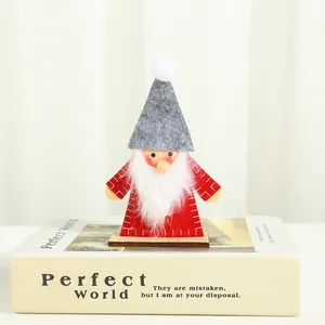 Handcrafted wooden Christmas gnome ornament with red felt coat and grey hat on white book