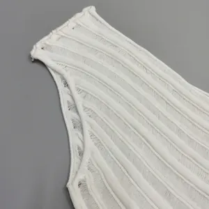Close-up of white ribbed knit dress featuring intricate hollow-out and off-shoulder detail.