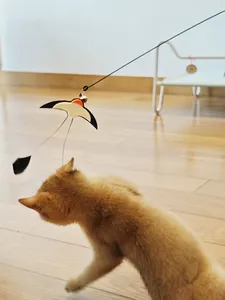 Detailed action shot of a swallow-shaped cat teaser wand toy with a bell and feather tail