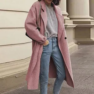 Street style view of a long pink woolen coat paired with blue jeans and sweater
