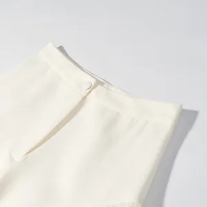 Close-up view of the minimalist cream lantern pants waistband with a matching button closure
