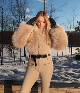 Detailed view of women's khaki slim-fit ski suit with plush faux fur jacket in snow