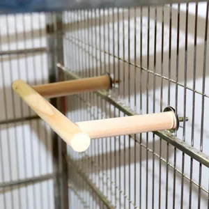 Close-up view of a T-shaped natural wood bird perch installed in a metal wire cage