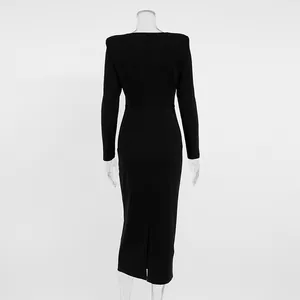Back view of elegant long-sleeved black midi dress with a back slit detail.
