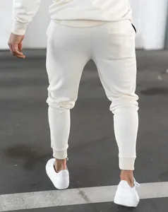 Rear view detail of cream athletic sweatpants paired with white sneakers