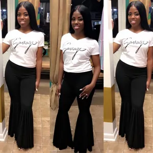 Modelo con camiseta blanca Savage y pantalones de campana negros con dobladillo de volantes.