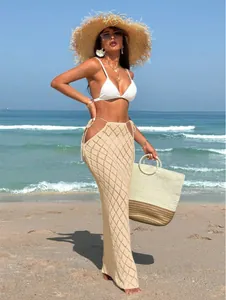Sexy beige crochet maxi skirt featuring side cut-outs and lace-up details on a beach